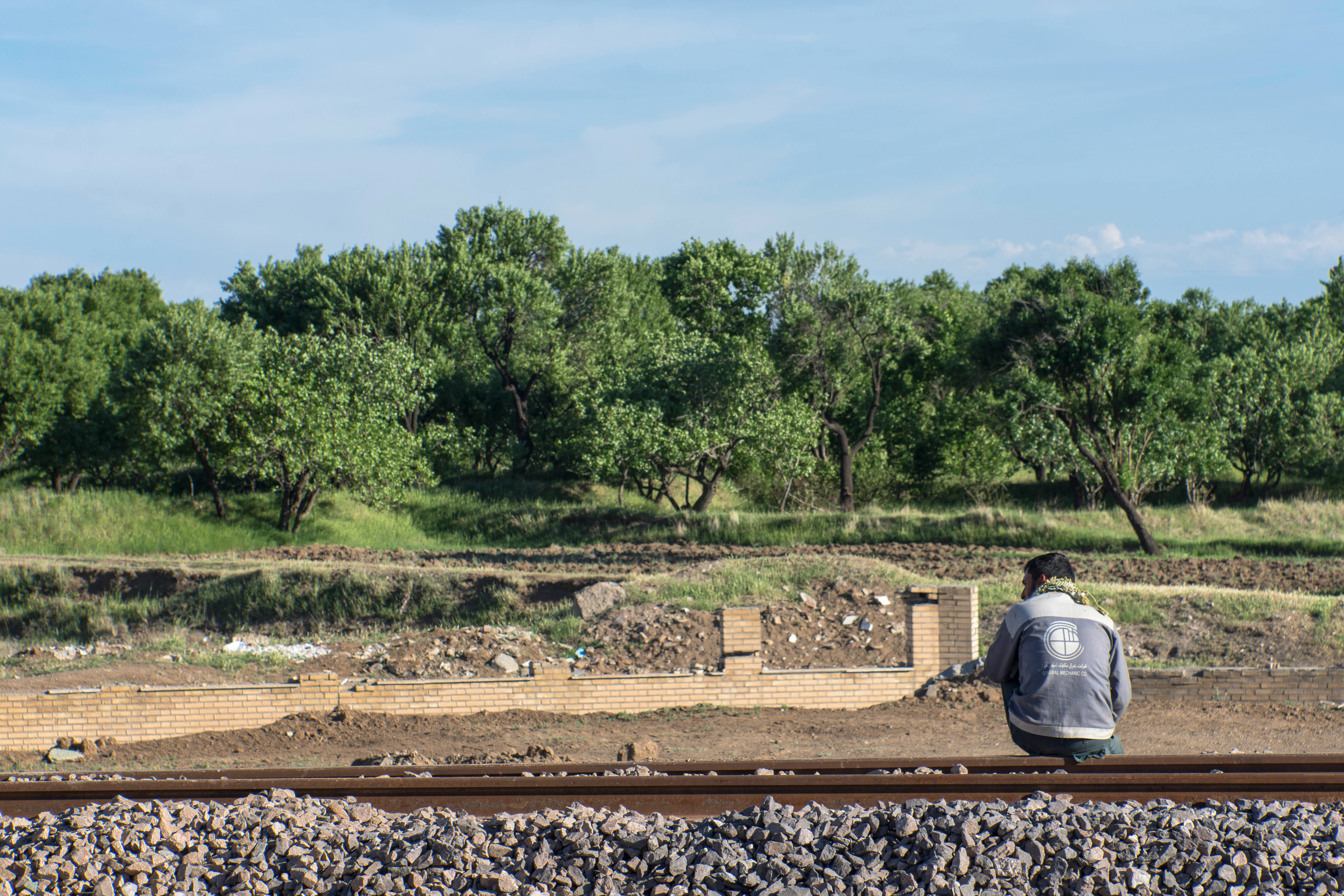 man in gray jacket sitting on brown wooden bench during daytime